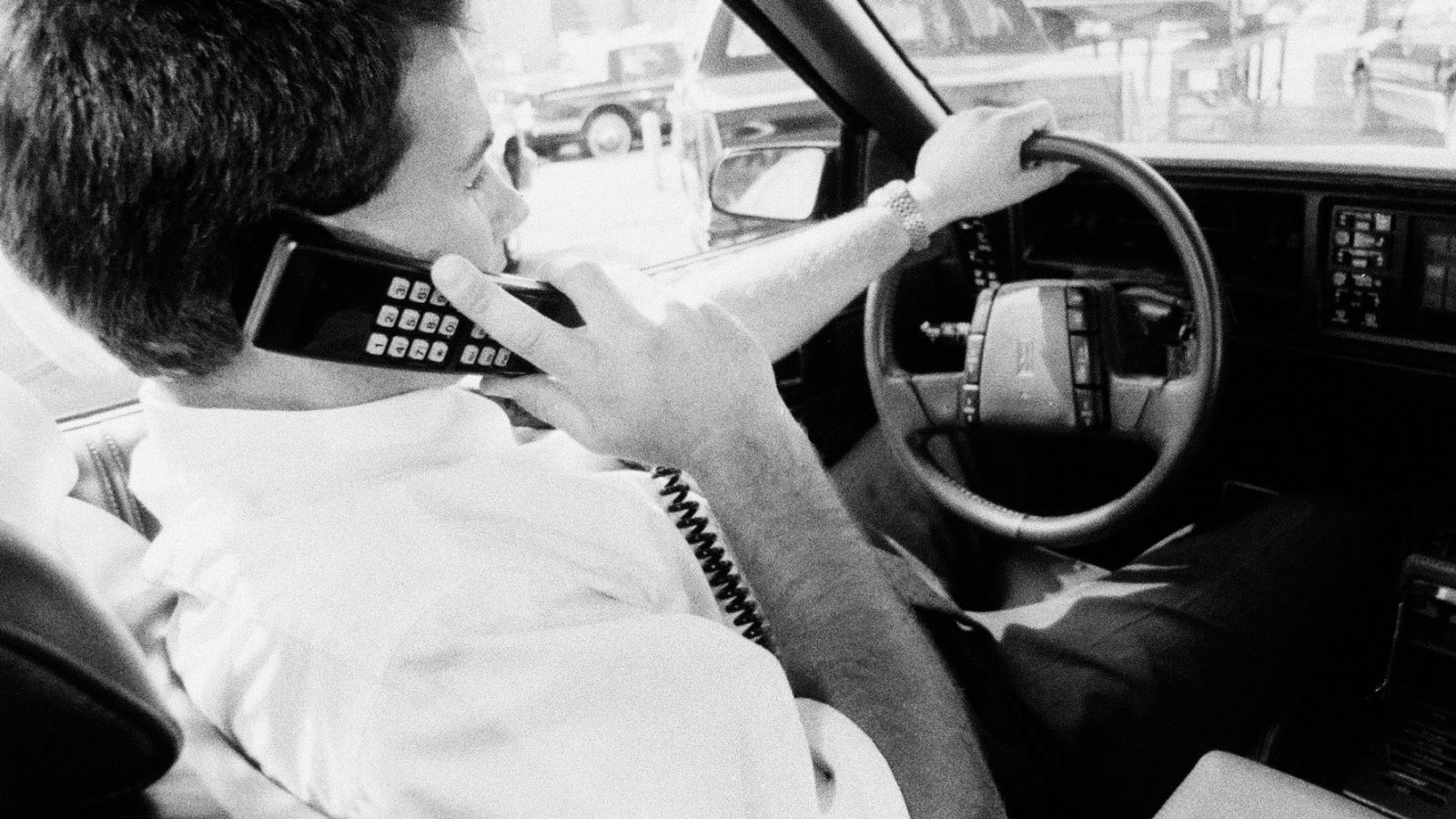 Al volante di un’automobile con uno dei primi telefoni cellulari (fonte: Ansa, La strada racconta, 2018)